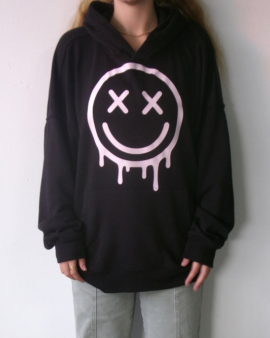 Front of the OUTSPOKEN Signature Hoodie in black with pink dripping smiley graphic
